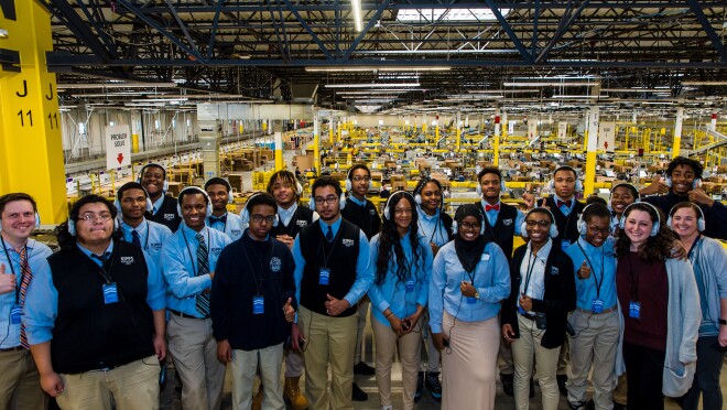 穿着校服的高中生们在参观亚马逊物流中心时摆出一组姿势。