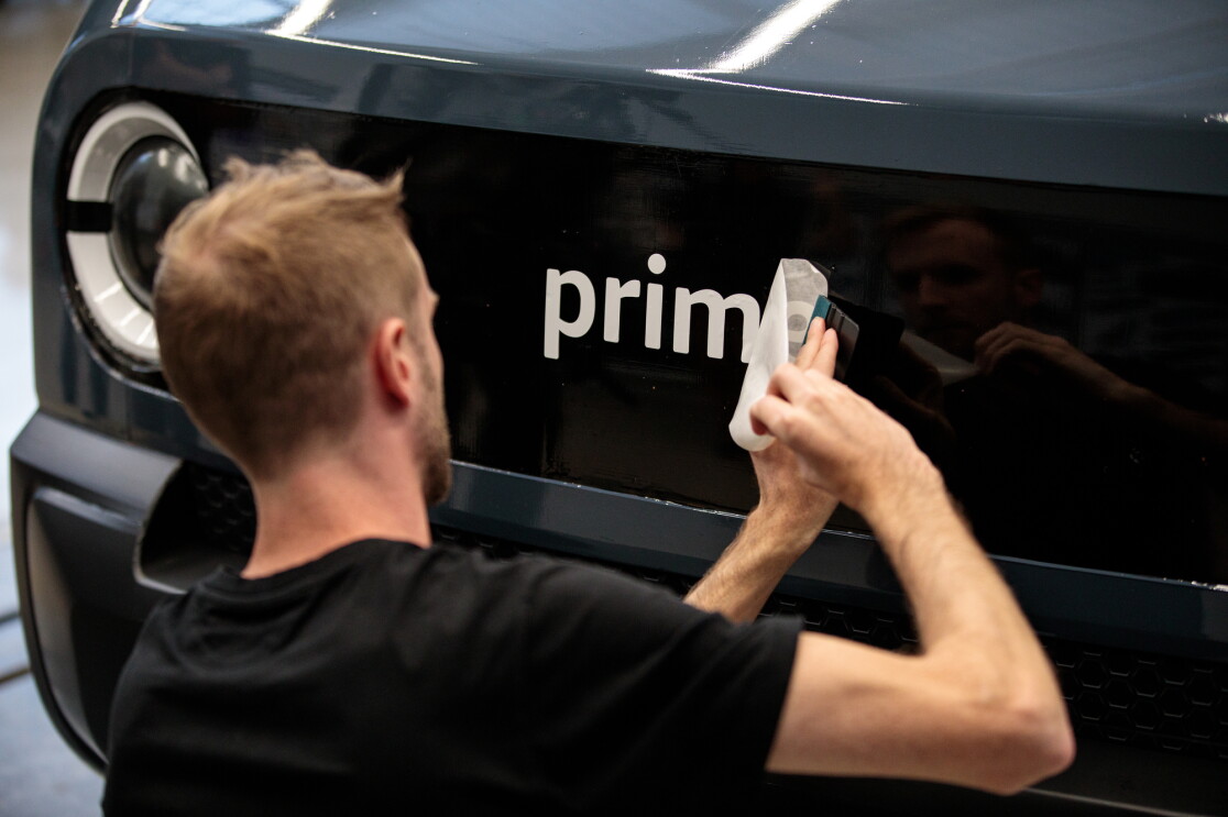 Ein Rivian Designer bringt einen Prime Schriftzug auf dem Tonmodell des Elektrolieferfahrzeugs an.