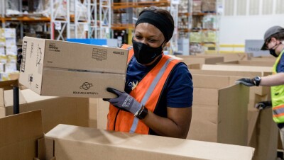 一个女人戴着面具和一个橙色安全背心,她把东西包被发送到乌克兰。