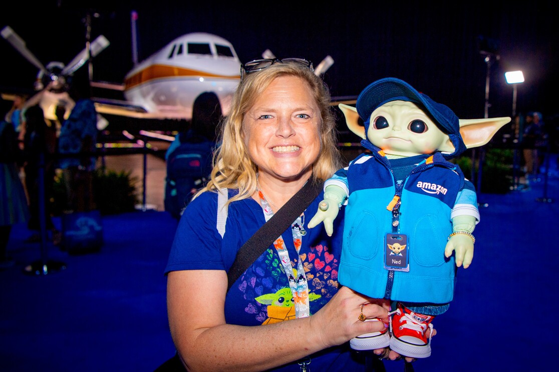An image of a woman holding a Grogu doll dressed as an amazon employee