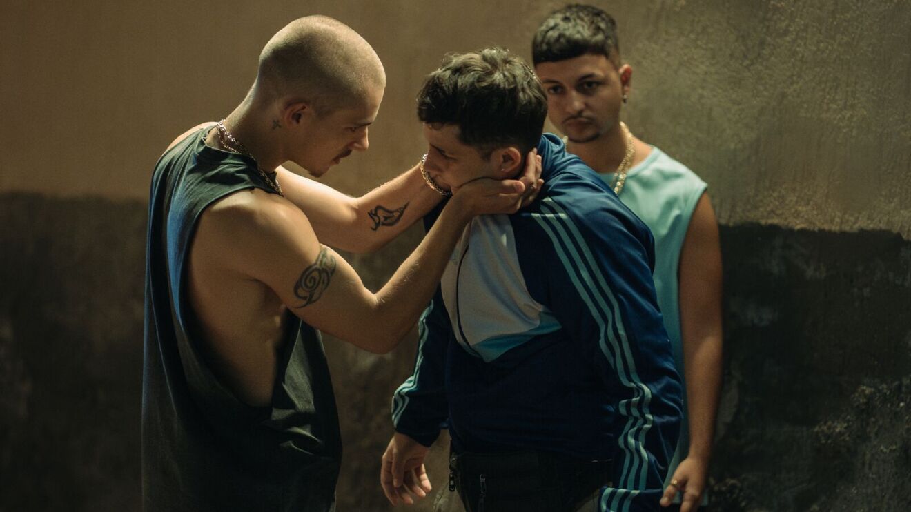 Two young men are in an uncomfortable encounter as a third man looks on