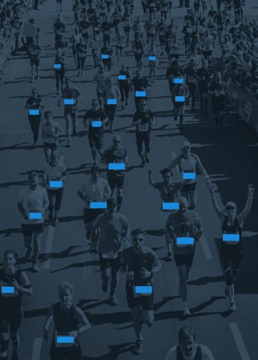 Viele Personen laufen in Sportkleidung auf einer Straße. Auf ihren Startnummern sind blaue Balken.