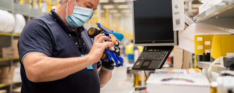 Ein Mann mit dunkelblauen T-shirt schaut sich ein blaues Spielzeugauto an.