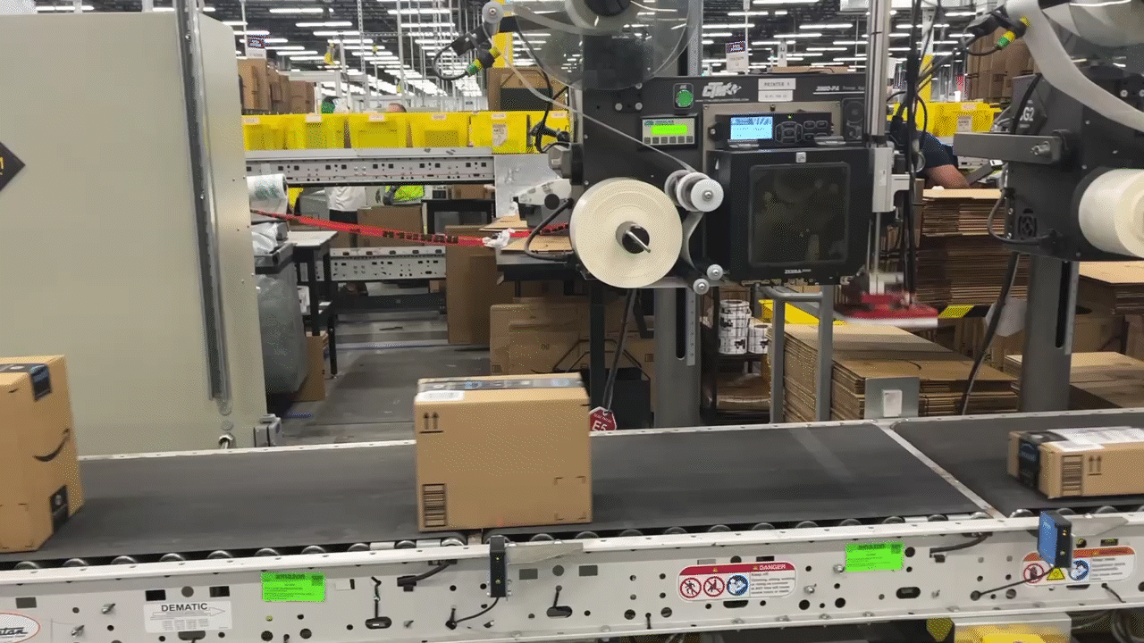 An animated GIF showing boxes move on a conveyer belt while being stamped with their shipping labels.