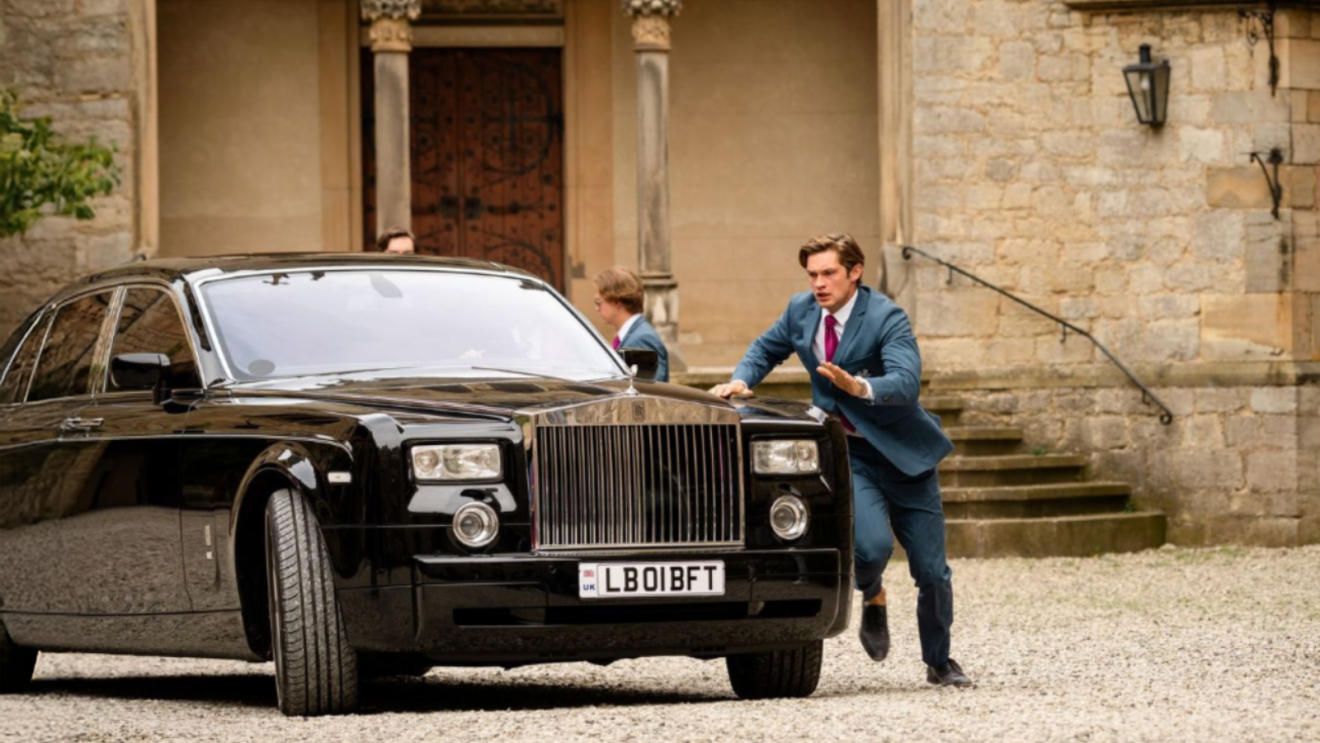 Damian Hardung as James Beaufort chasing a black Rolls-Royve outside the front of the school in Maxton Hall Season 3