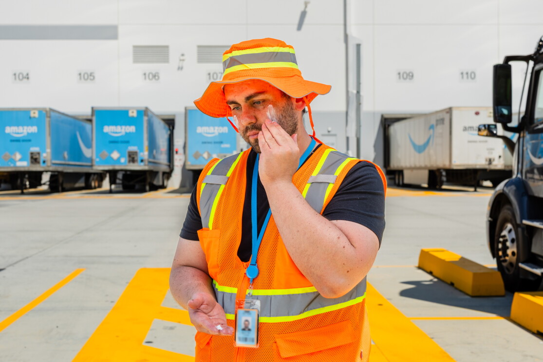 Amazon warehouse worker in safety vest and hat standing at loading dock