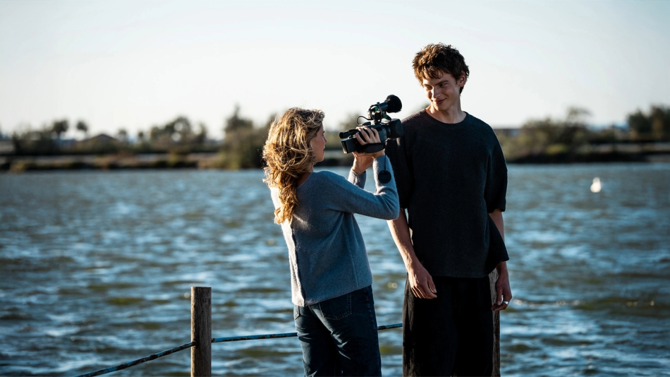 Vittoria De Savoia as Alma filming with a camera Lucas Barski (Vadim) by the coast in Prime Video's Carrousel