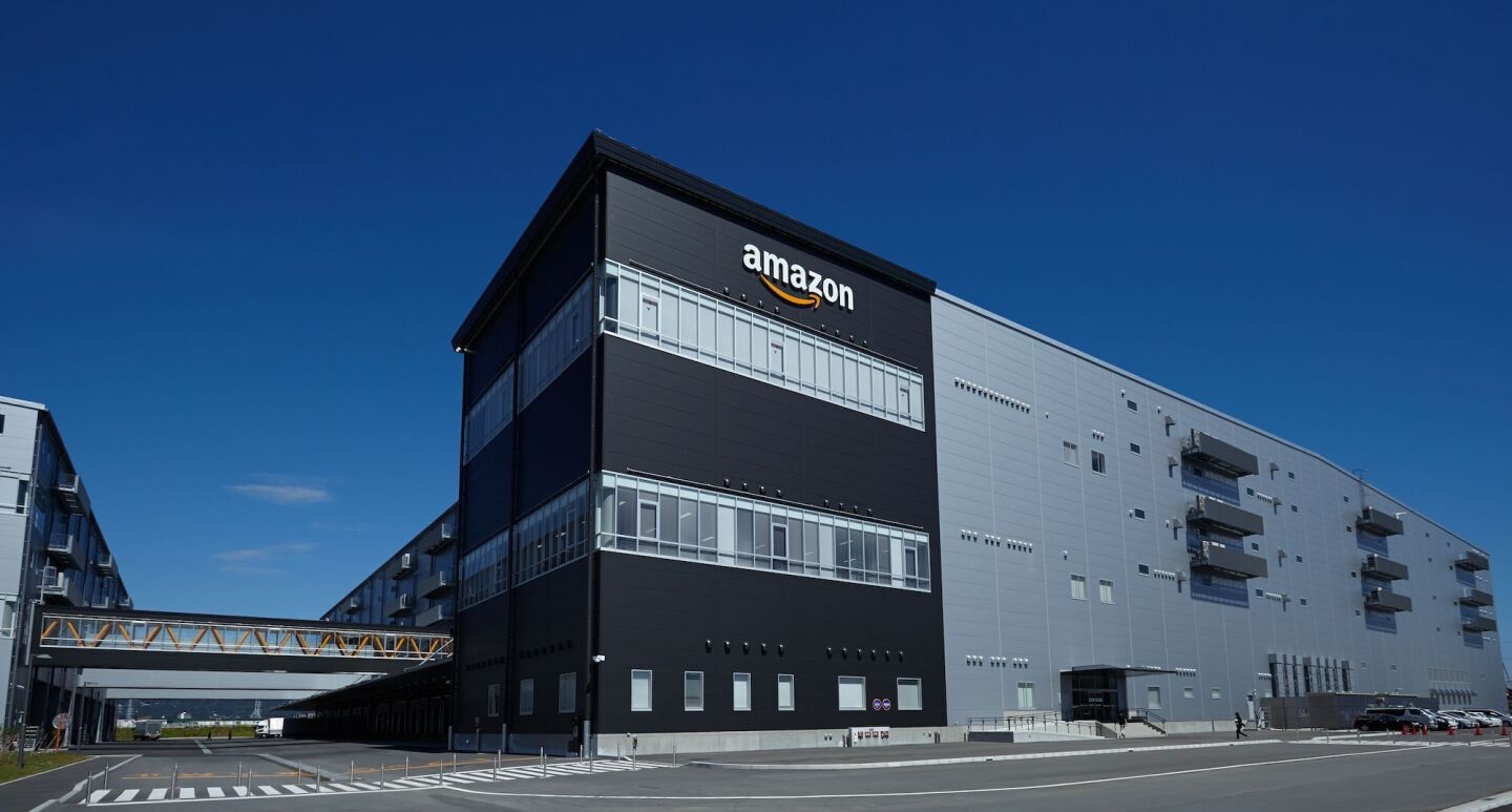 View of an Amazon Fulfillment Center from outside showing a multilevel facility with a skyway linking two buildings across an access street