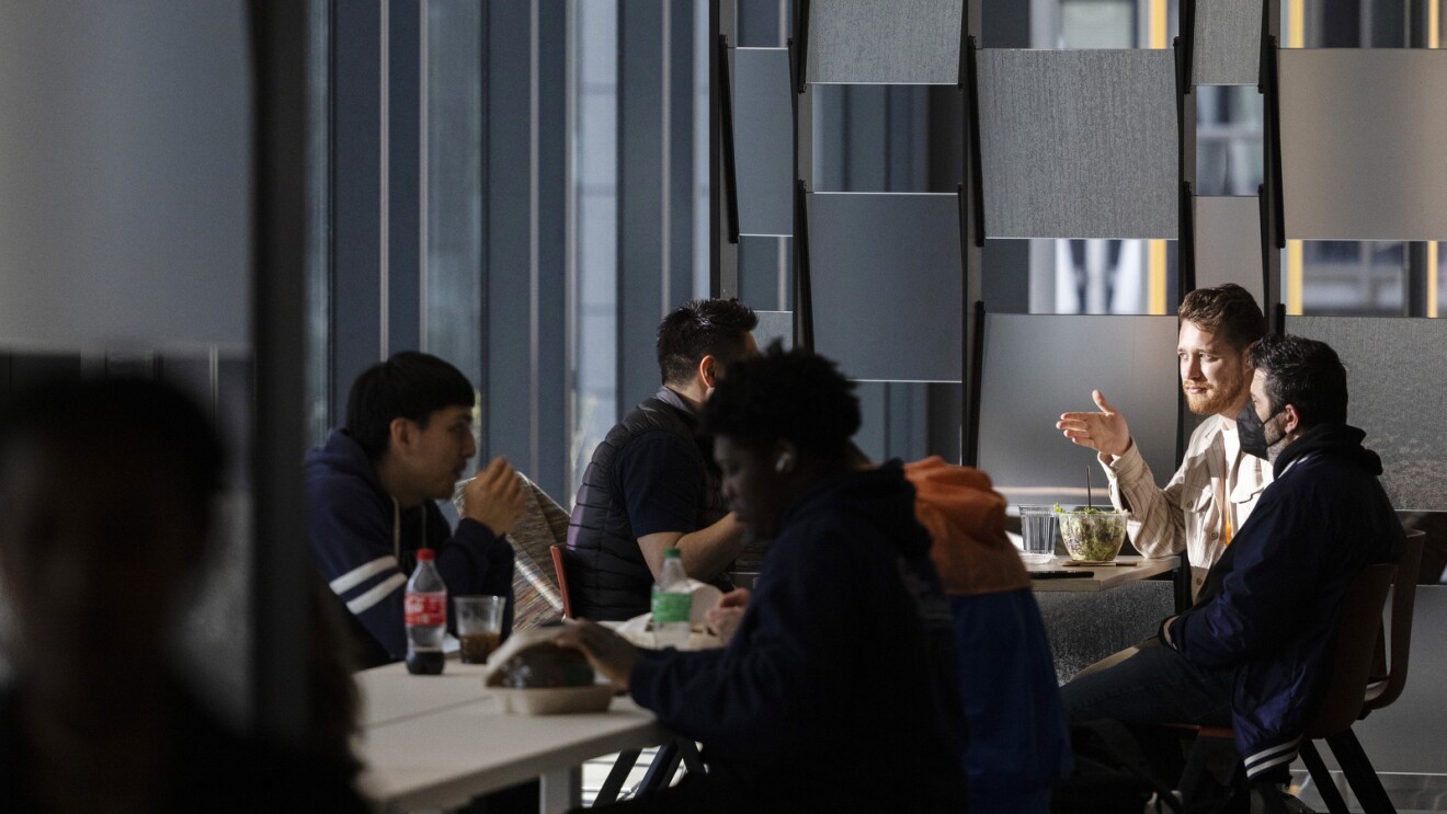 Employees sit and eat lunch at a table in an Amazon office.