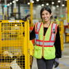 Amazon fulfilment centre team member in a high vis jacket standing with a cart of items