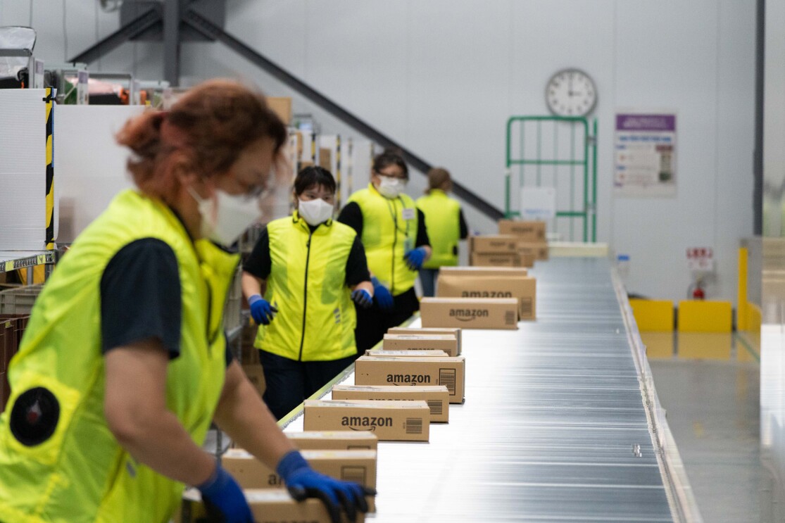 黄色いベストを着たAmazonのデリバリーステーションのスタッフたちが商品を仕分けしている