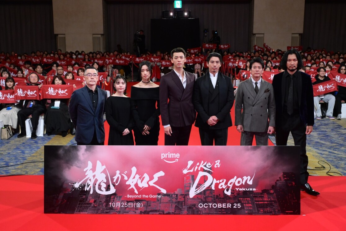 黒いスーツやドレスをまとった出演者6人と監督。その後ろに「龍が如く」のロゴが入った赤いタオルを持つ数百人の観客