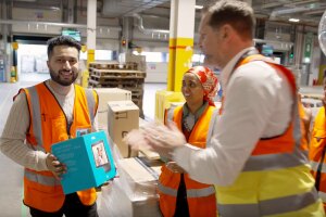 Sohil holds a gift while his team claps in an Amazon fulfillment center.