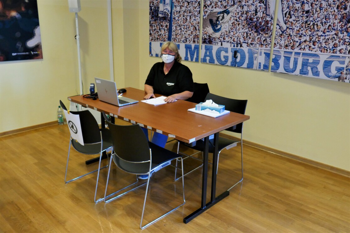 Eine Mitarbeiterin mit Munschutz an einem Tisch.