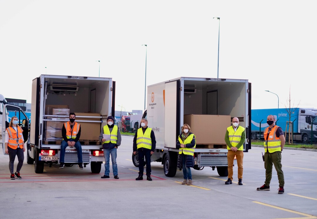 Mitarbeiter von Amazon und der Tafel vor 2 Tafel-Lieferwagen.