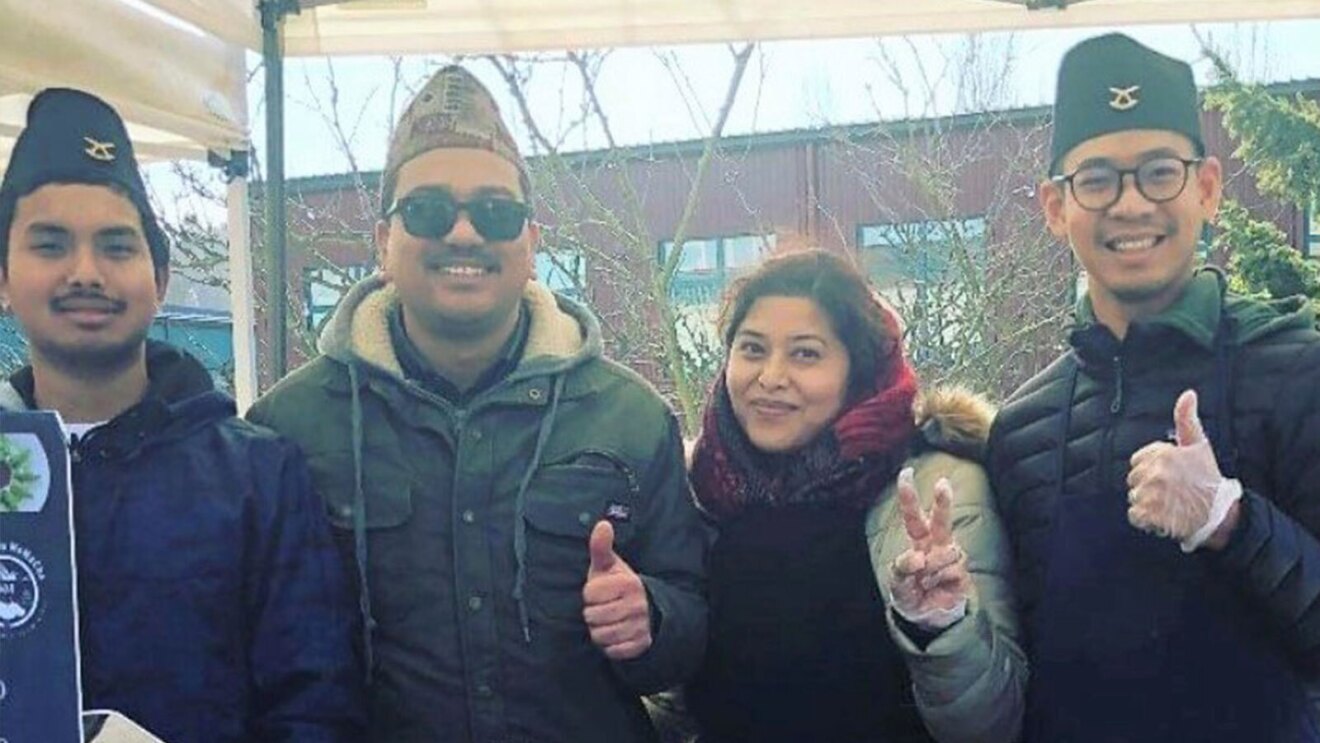 Four people stand smiling for a photo outside.