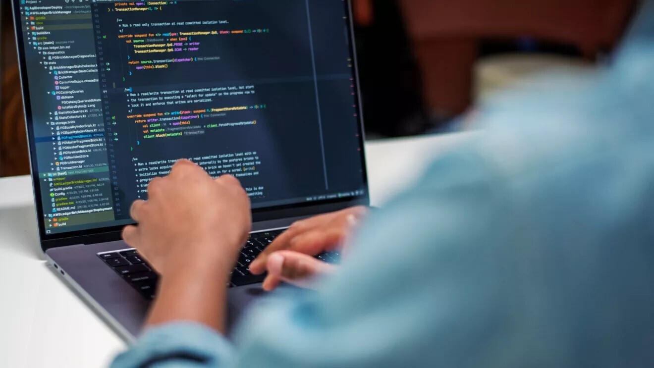 Imagen de un ordenador en el que se ve que uan silueta difuminada está programando. 