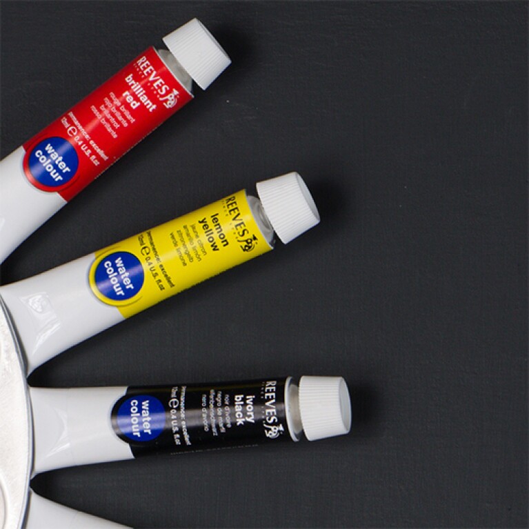 Three tubes of paint are arranged in a radial pattern. The top tube is labeled "brilliant red." The middle is "lemon yellow." The bottom is "ivory black."