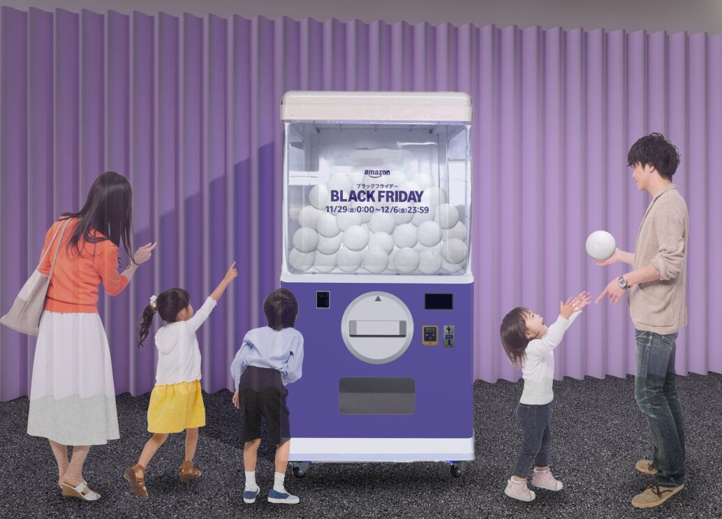 会場のイメージ図。Black Fridayと書かれた巨大なカプセルトイが紫色の壁の前に置かれている。そのガチャの前に女子と男子、そしてカプセルトイを指差している女性が立っている。カプセルトイの右側には、カプセルを持った男性が小さな女子に渡そうとしている