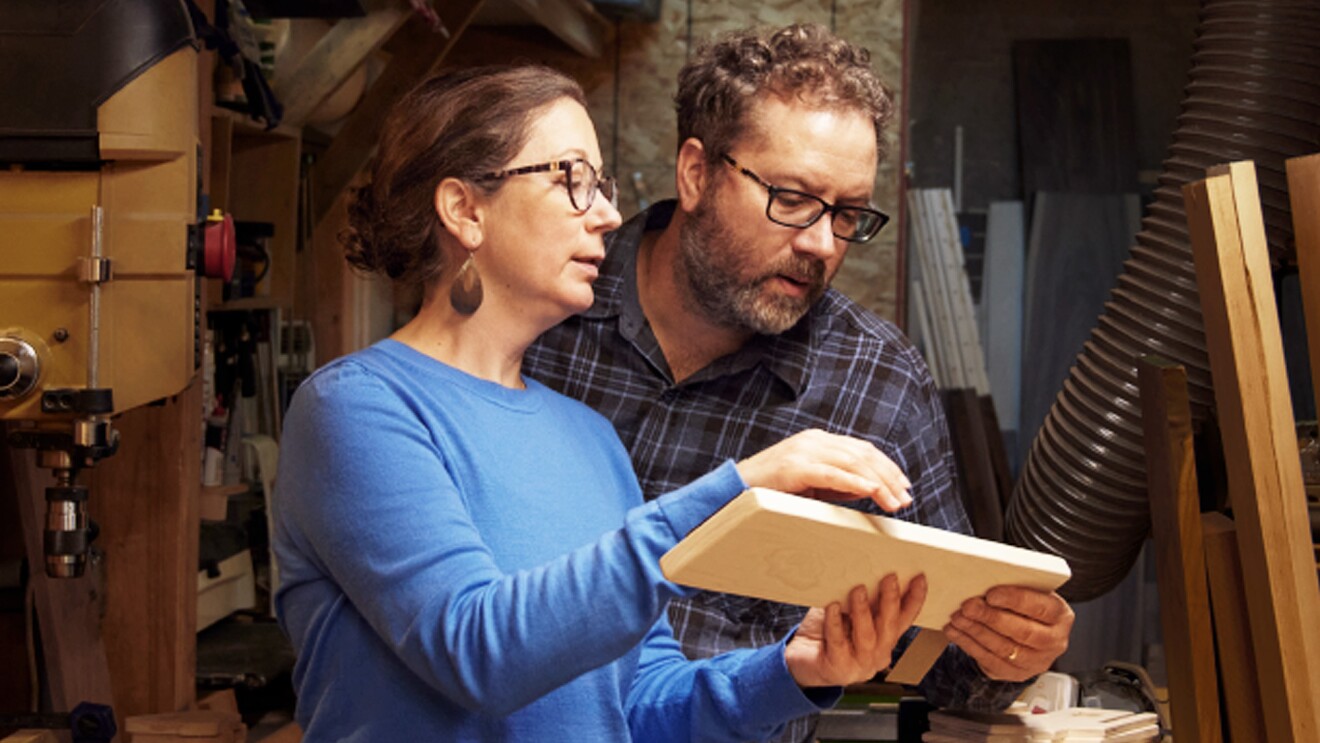 A man and a woman look at a piece of wood together.