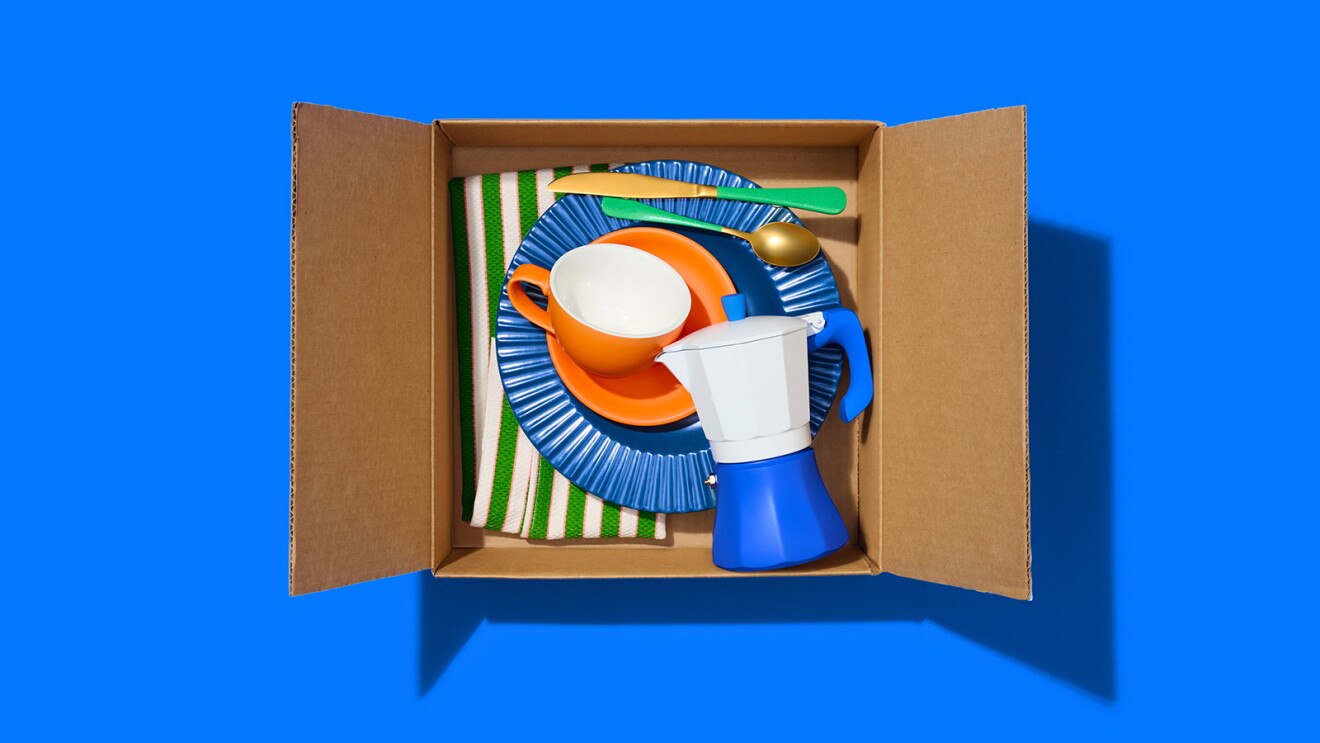Colorful kitchenware packed in cardboard box against blue background