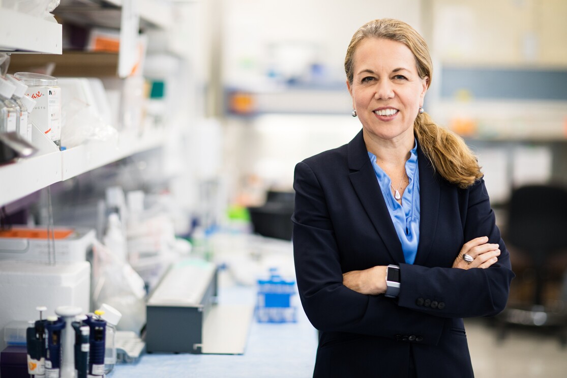 An image of a woman smiling for a photo in a research lab. 