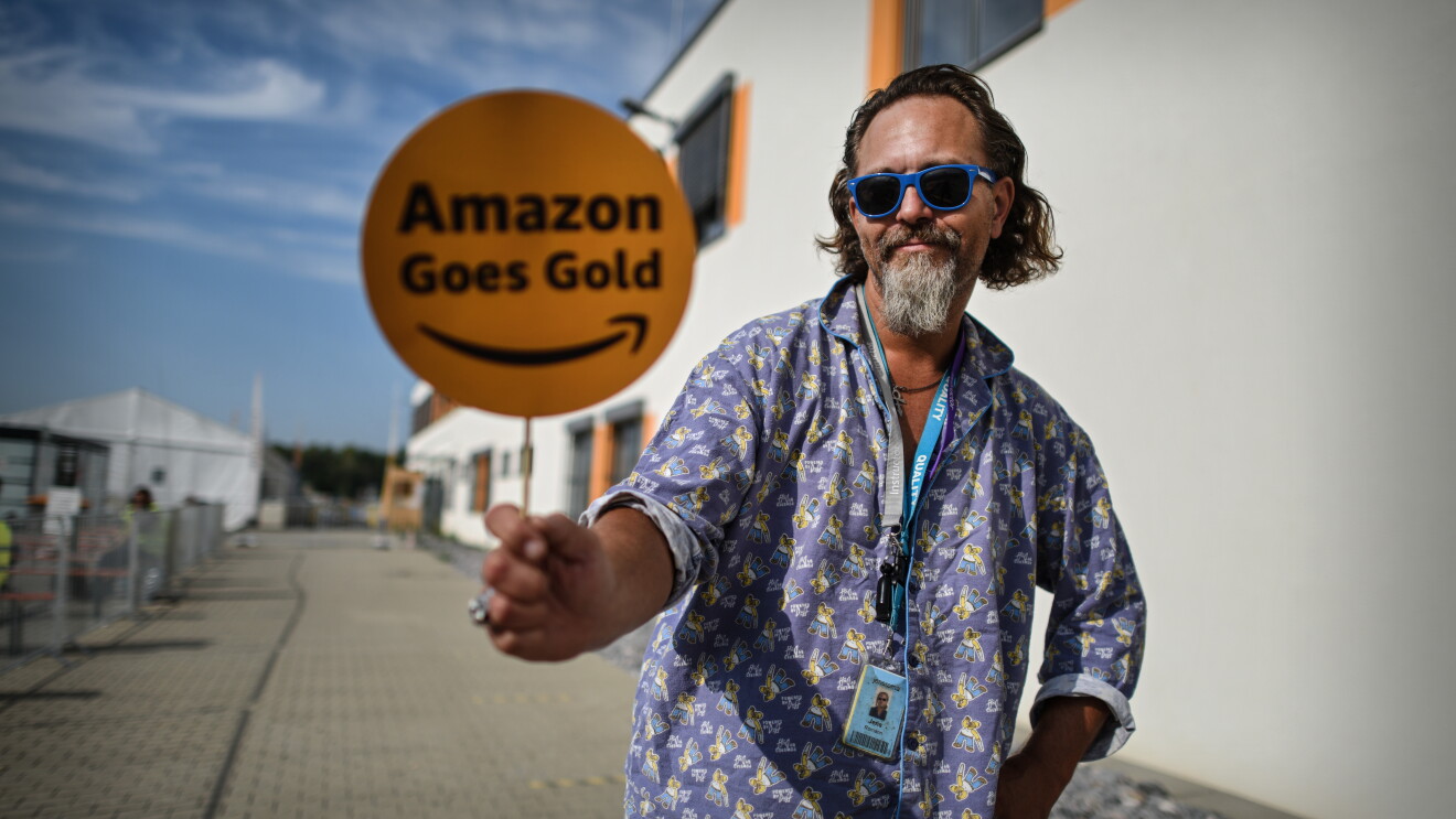 Amazon Mitarbeiter im Schlafanzug mit Amazon Goes Gold Schild