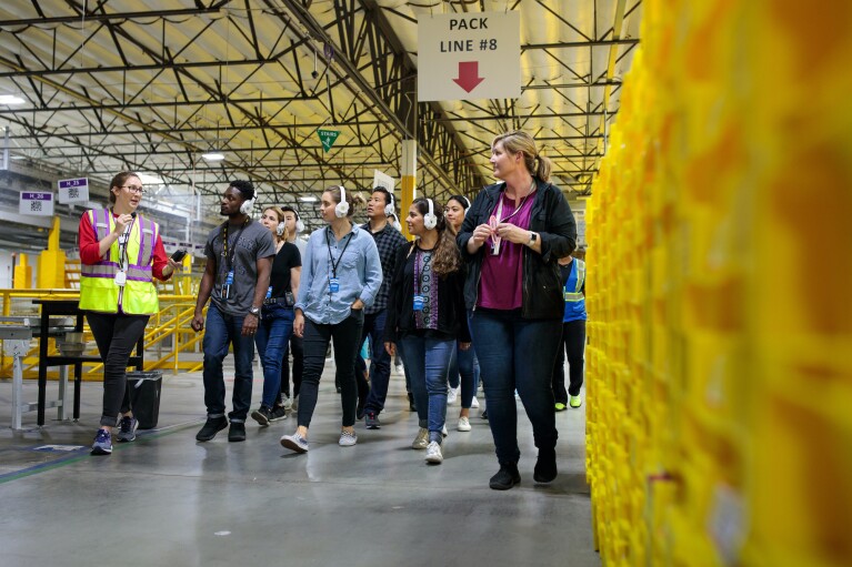 A photo of an Amazon employee give a guided walking tour of an Amazon Fulfillment center.