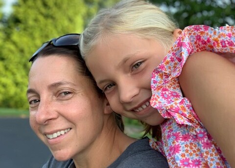 Andi and her daughter, Katelyn, pose for a picture together outside. 