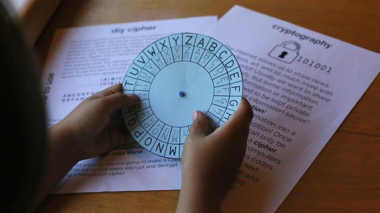 A student holds a paper cypher in his hand, as he learns about STEM education.