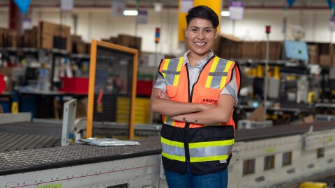 Trabajdora de un centro logístico de Amazon delante de una cinta transportadora.