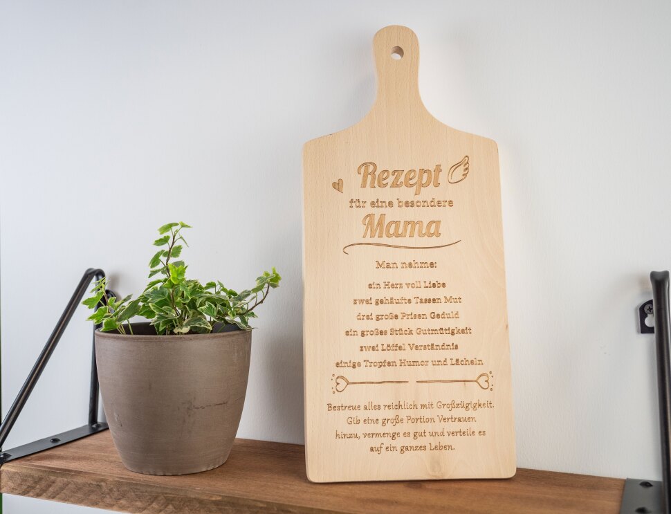 Auf einem Regal steht ein Holzbrett mit der Aufschrift "Rezept für eine besondere Mama"
