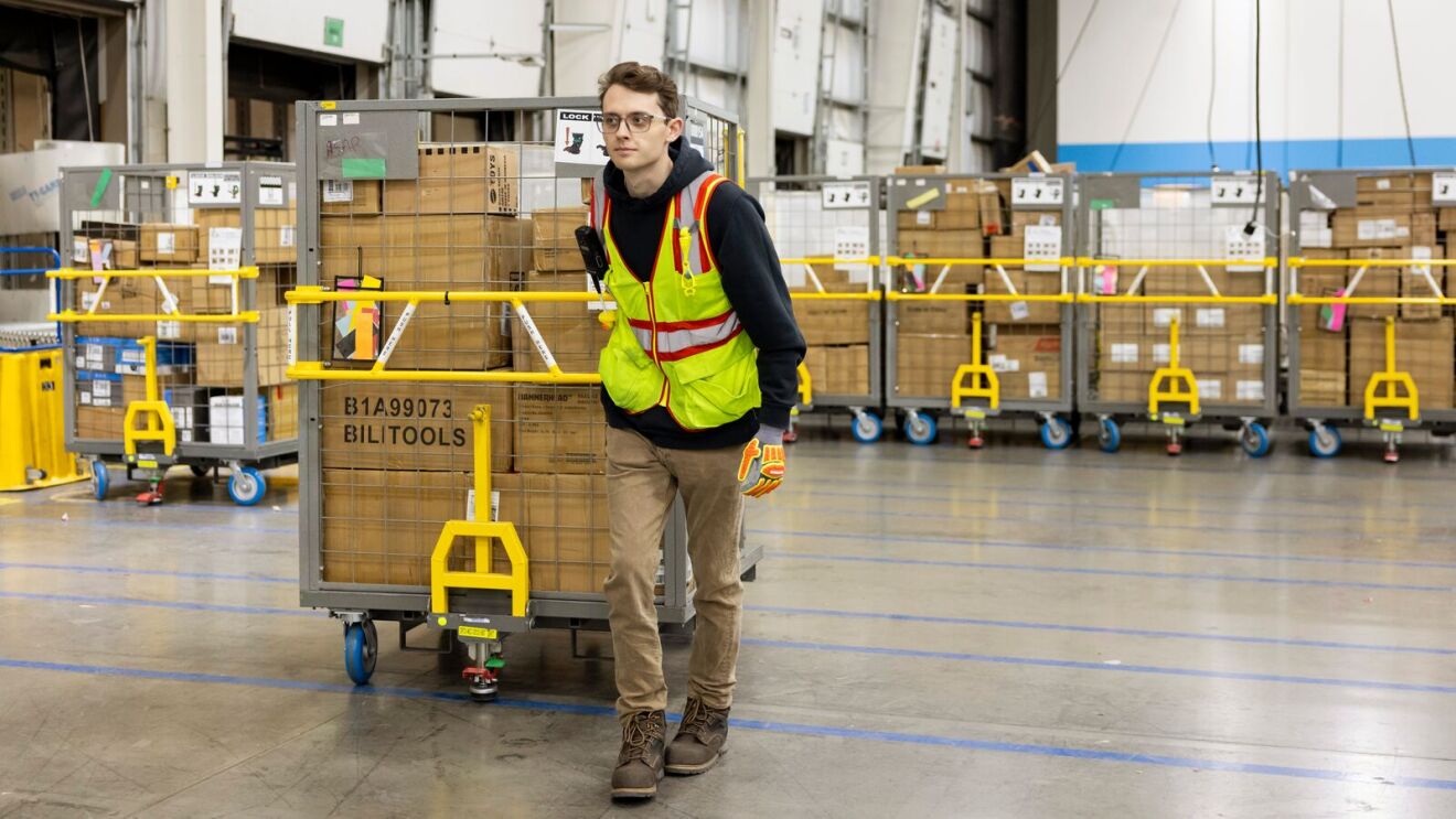 Employee navigating through stacked inventory in large warehouse.