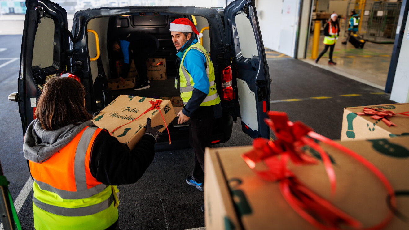 En un centro logístico de Amazon hay un trabajador con un gorro de Papá Noel cargando una furgoneta con las cestas de comida.