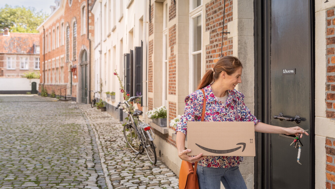 picture of a woman carrying a box and entering a home