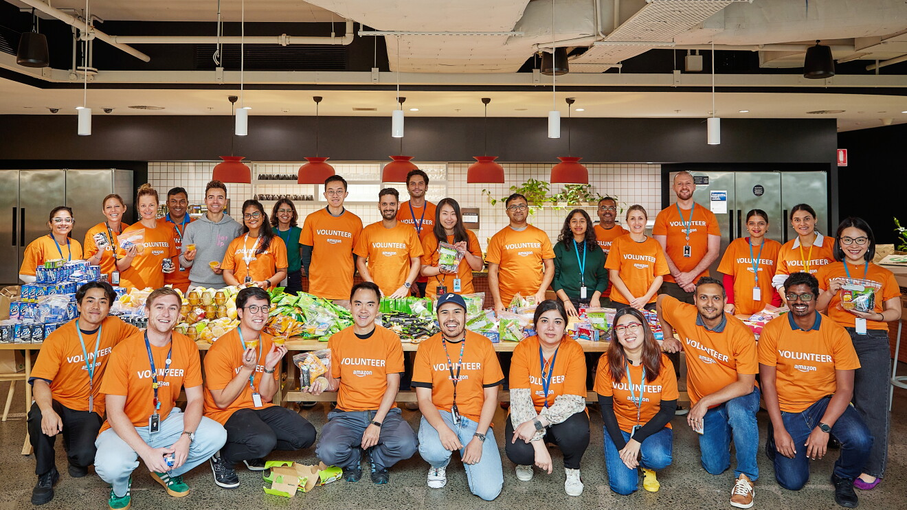 Diverse group of volunteers in orange shirts gathered around food donations in Australia