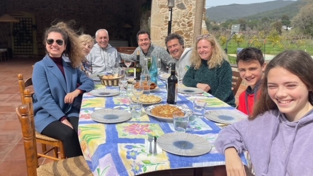 Daria sits a dinner table outside in Spain alongside her parents, and an Amazon colleague and his family.