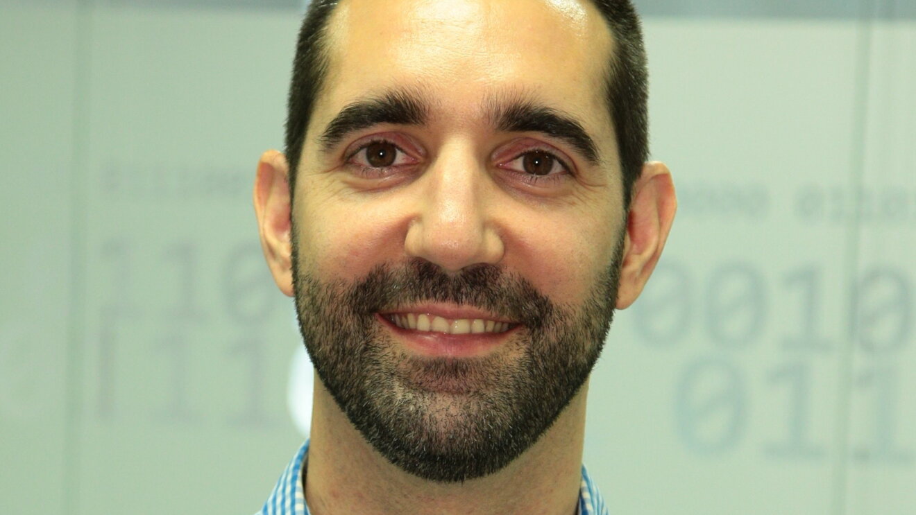 Primer plano de Gorka Rodríguez sonriendo y con una camisa de cuadros azul y blanca.