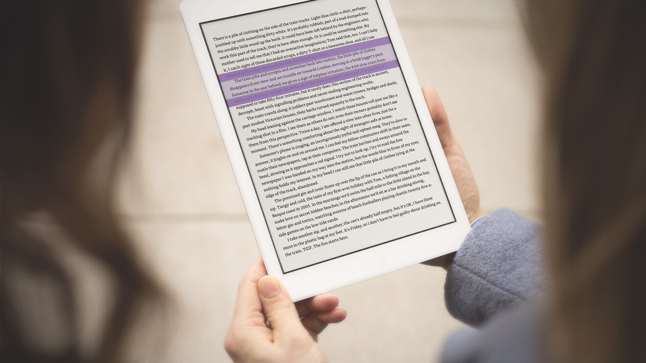 A person holds a Kindle device in their hands, while highlighting text with the Kindle Ruler.