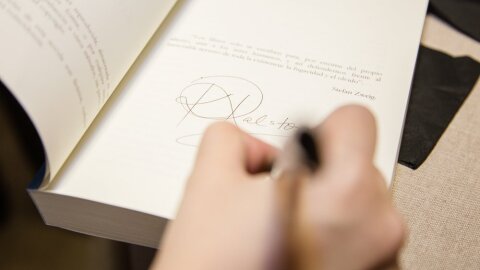 Una mano con un bolígrafo dedica un libro con su firma.