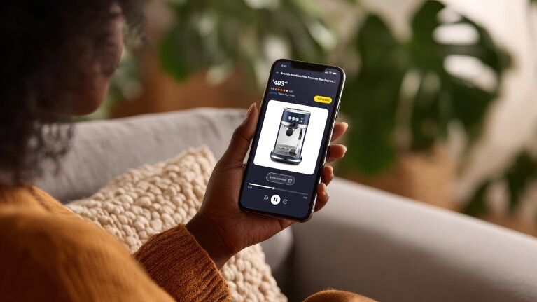 Person holding smartphone displaying Amazon listing of espresso machine product priced at $483
