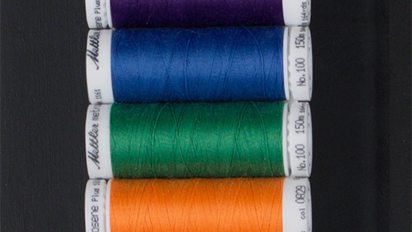 Spools of thread in a range of colors: gray, purple, blue, green, orange, and red.