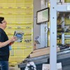 Employé d'entrepôt tenant un guide de Paris près d'un système de tri automatisé