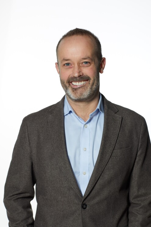 Man in grey jacket smiling at camera 