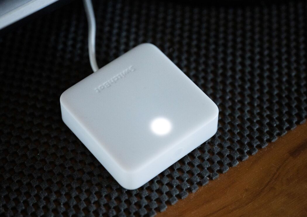 木製のテーブルの上にひかれた黒い滑り止めシートの上にプラスティック製の白く平たい立方体の一点が白く光っている