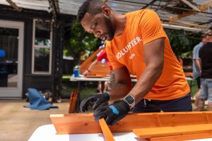 Amazon employee wearing orange 'Volunteer' t-shirt constructing with lumber