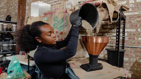 一个咖啡师咖啡豆子倒进一个大咖啡研磨机。