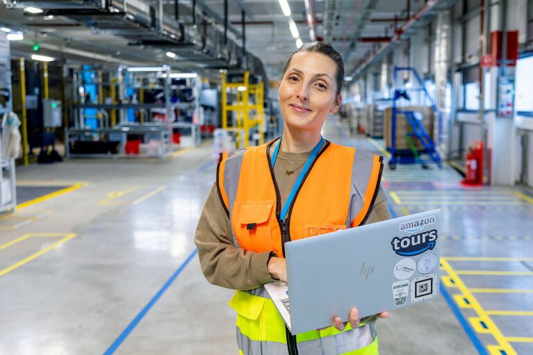 A woman standing holding her laptop and smiling in an FC