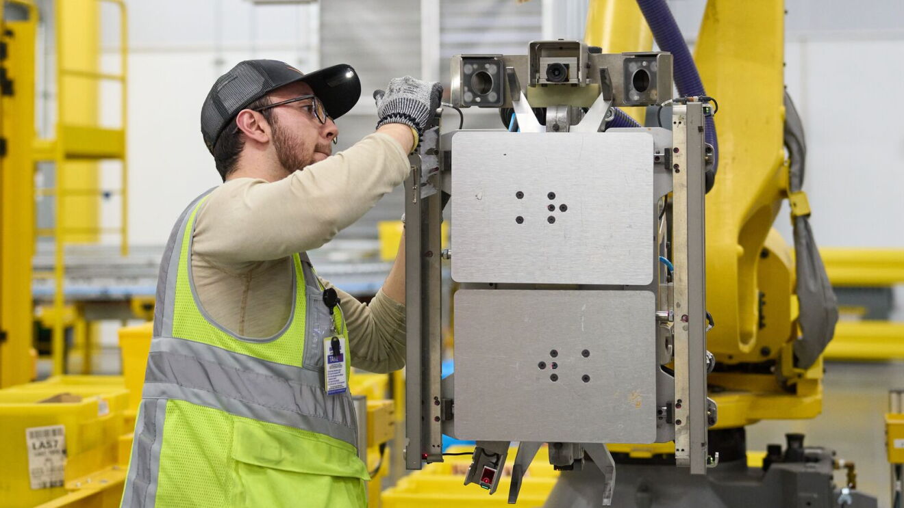 An employee working with a robotic system in an Amazon fulfillment center