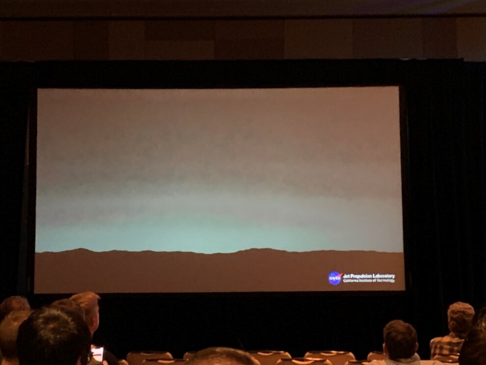 A screen at a conference center, shows the view from Mars.